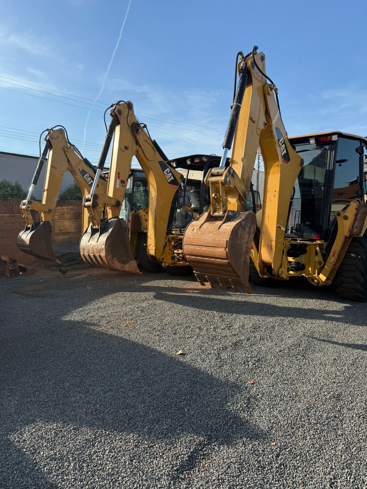 Frota de retroescavadeiras Caterpillar da GR Imada alinhada no pátio