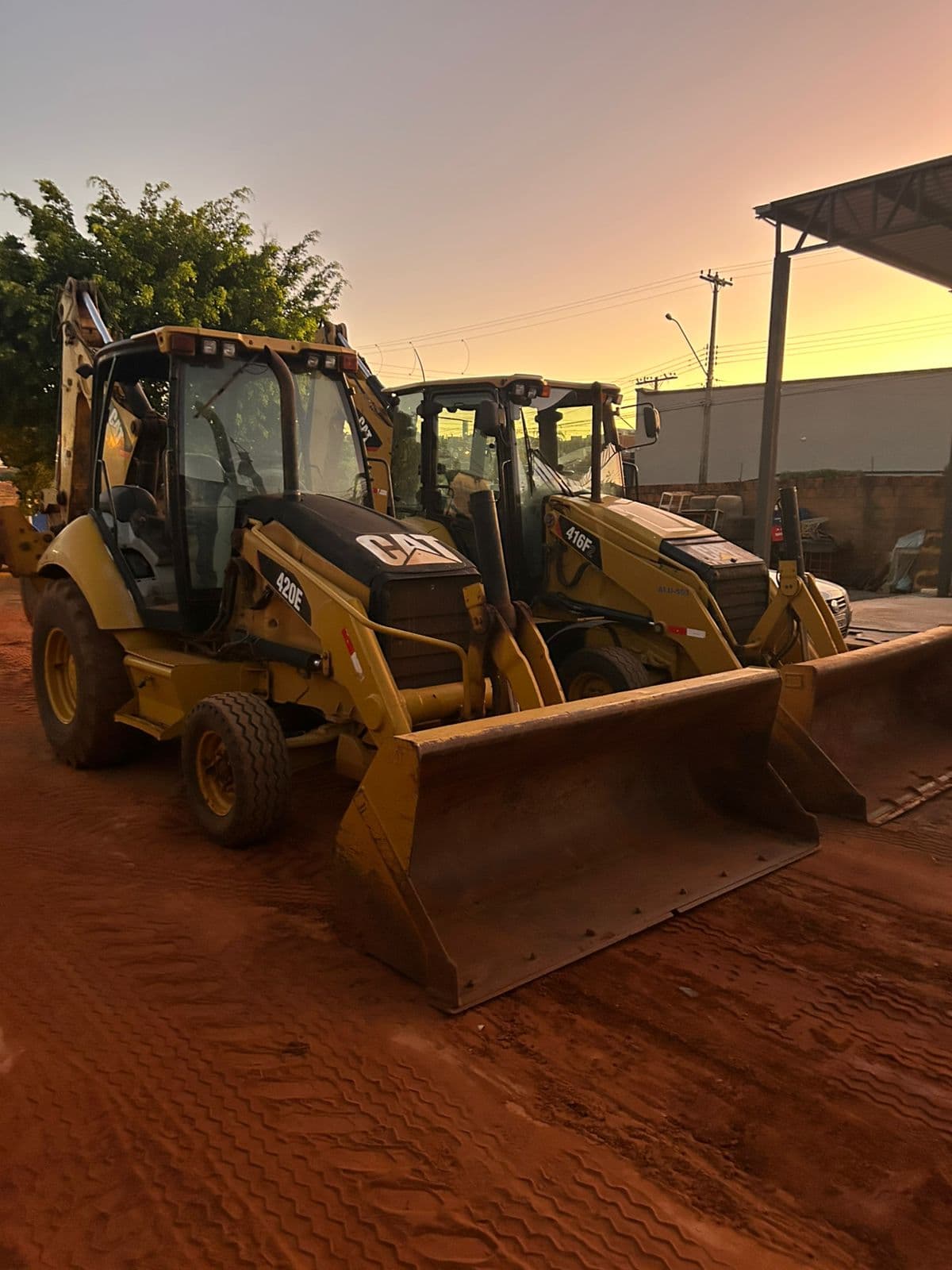 Retroescavadeiras Caterpillar da frota GR Imada ao entardecer no pátio